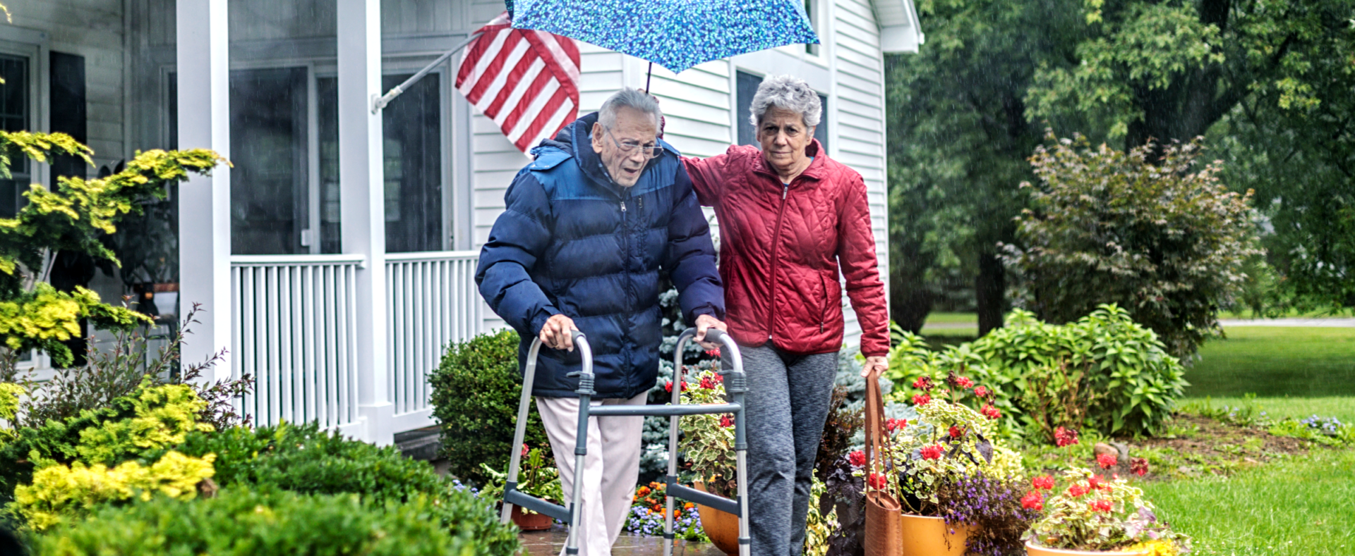 Woman helping older man walk in the rain